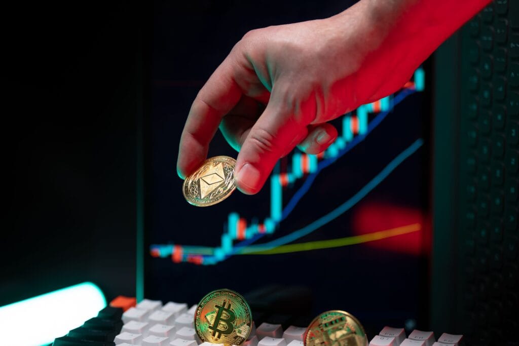 A hand holding cryptocurrency coins with a financial chart in the background, depicting market trends.